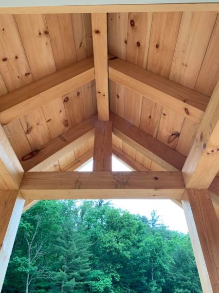 Wooden roof structure with forest view.