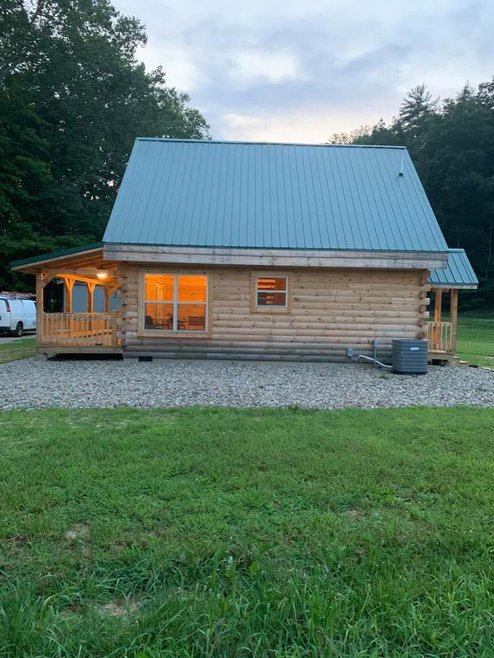 Log cabin with lit windows at dusk.