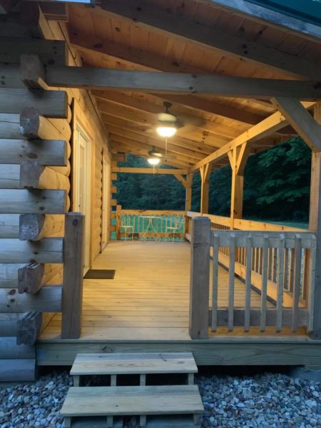 Wooden cabin porch with ceiling fan lights.