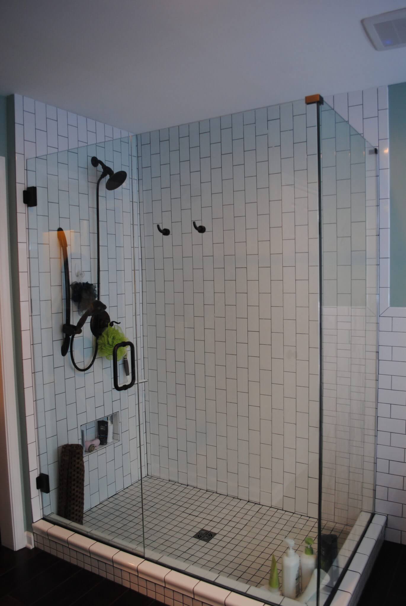 Glass-enclosed shower with black fixtures and tiles.