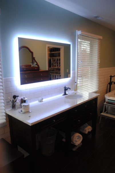 Modern bathroom with illuminated mirror and sink.