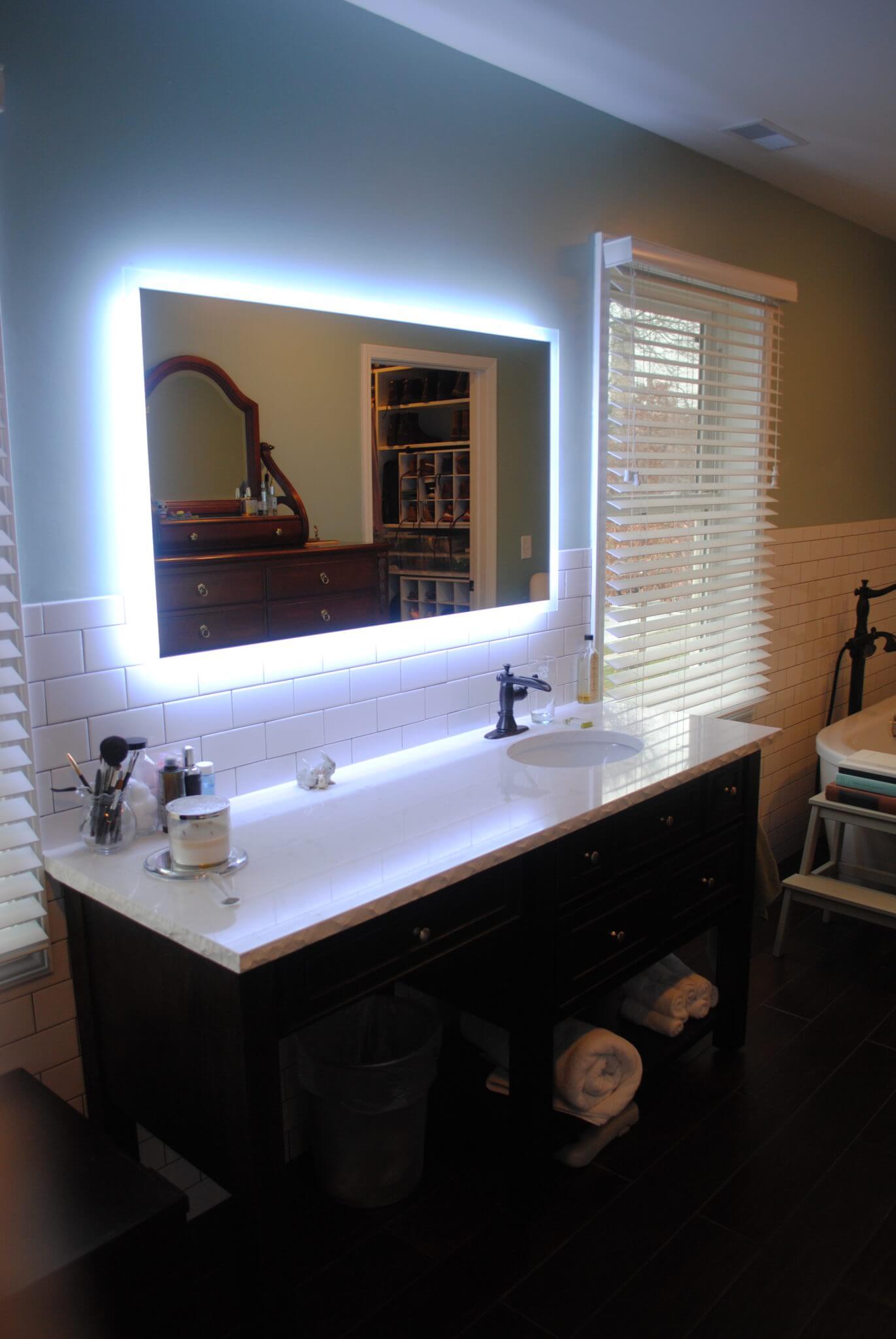Modern bathroom with illuminated mirror and sink.