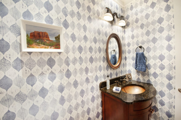 Elegant bathroom with patterned wallpaper and mirror.