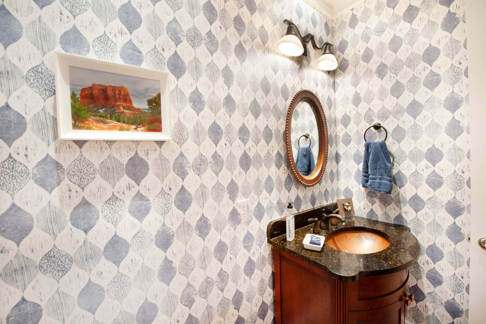Elegant bathroom with patterned wallpaper and mirror.