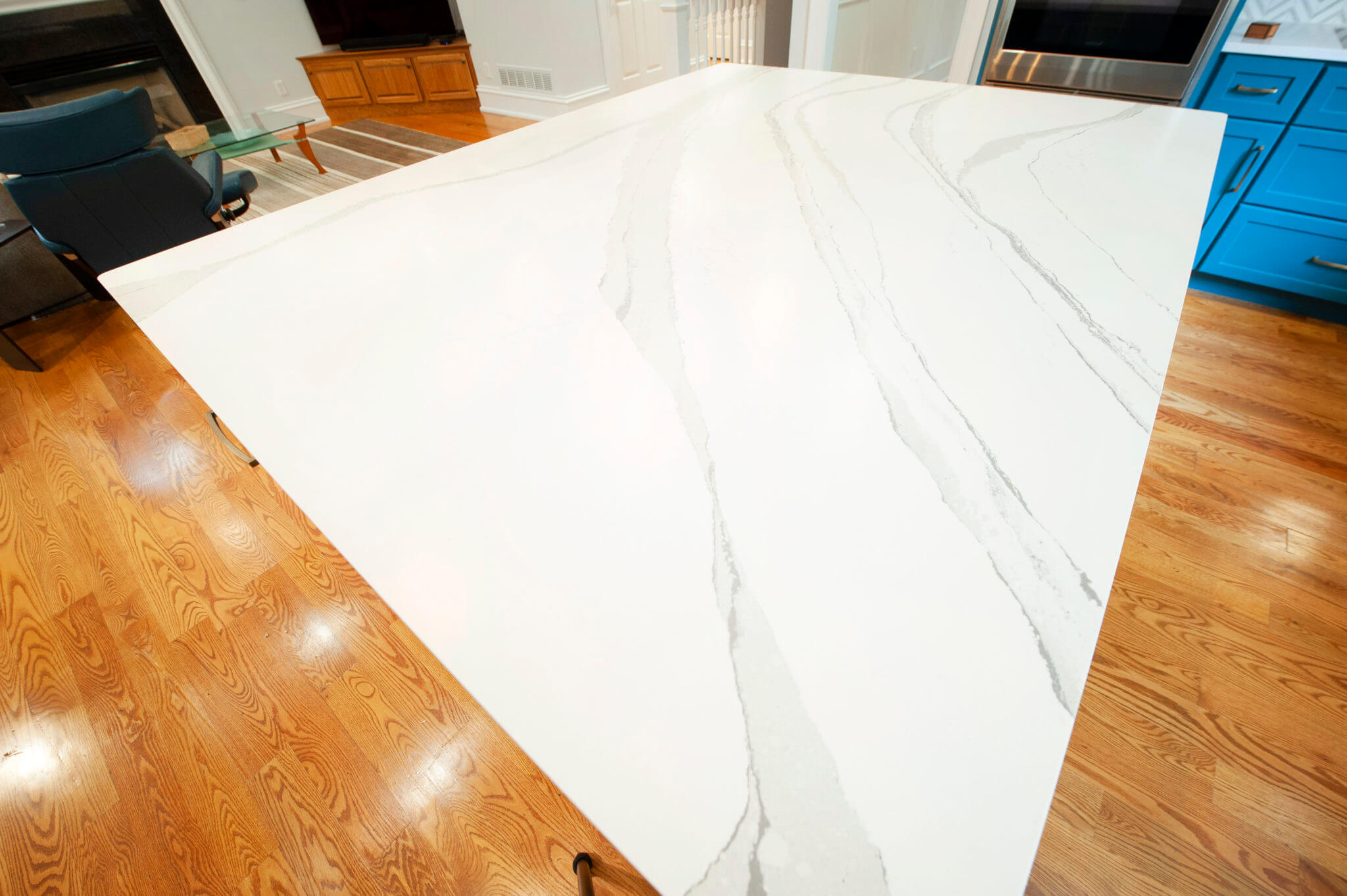 White marble kitchen countertop, wooden floor, blue cabinet.