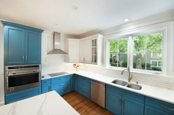 Modern kitchen with blue cabinets and windows.
