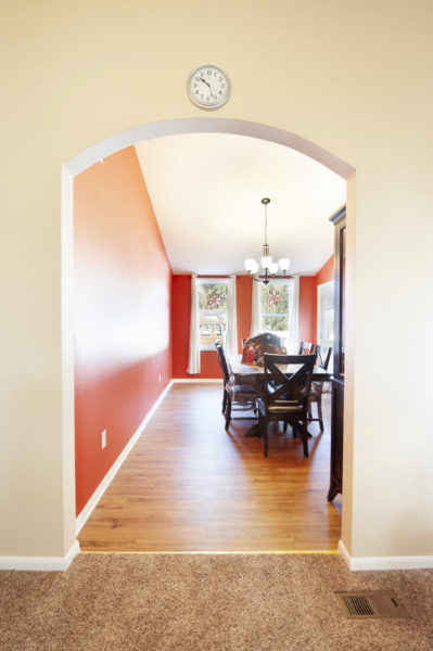 Dining room with wooden floor and archway.