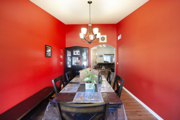 Red dining room with table and chandelier.