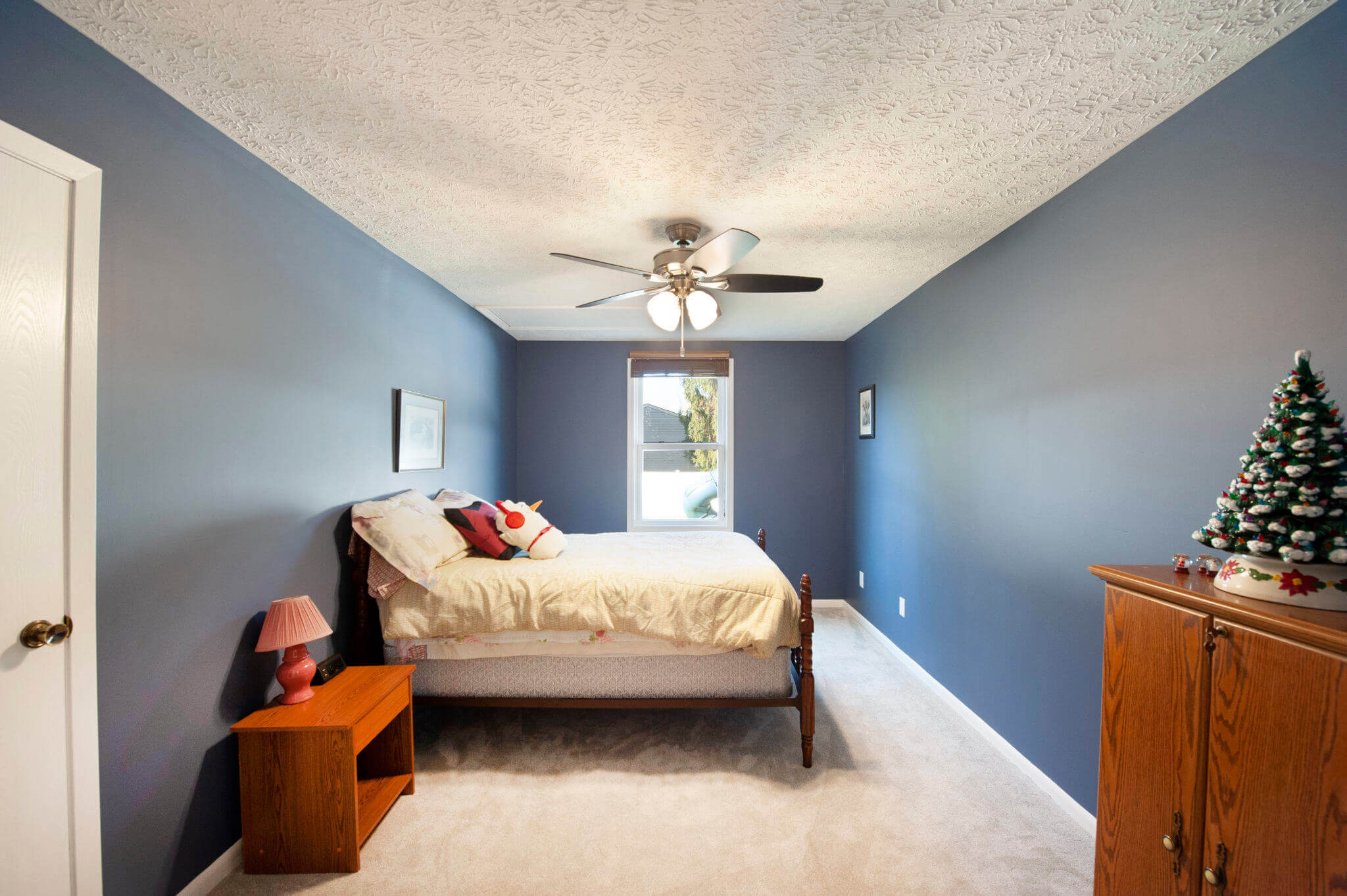 Bedroom with blue walls and ceiling fan.