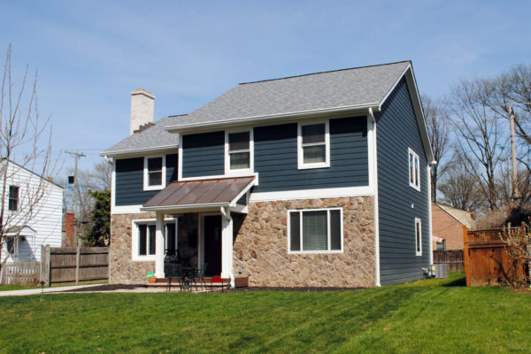 Blue house with stone facade and lawn.