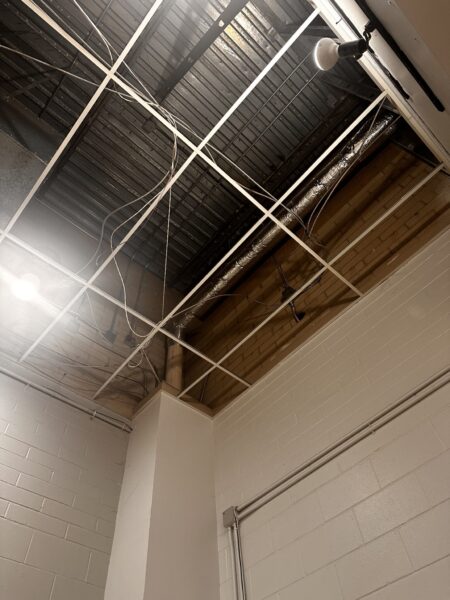 Exposed ceiling with wires and pipes visible.