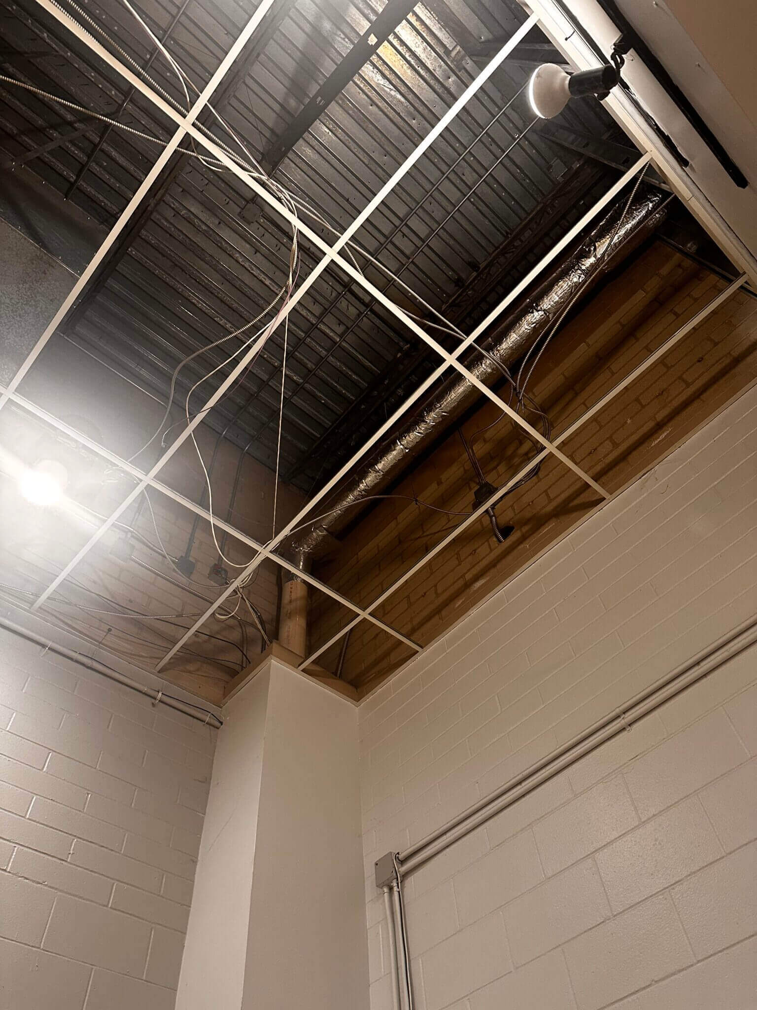 Exposed ceiling with wires and pipes visible.